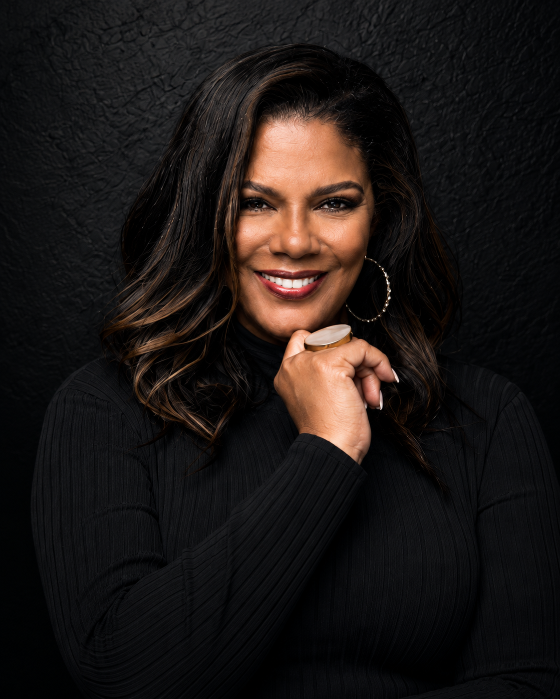 Barbara Clarke-Ruiz smiling in a black top, her hand resting beneath her chin